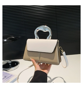 Détail du sac à bandoulière bicolore avec poignée géométrique en métal argenté