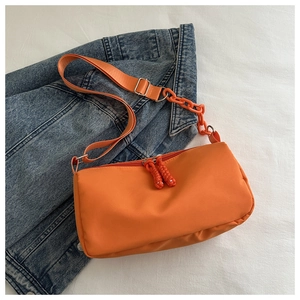Top view of bright orange crossbody bag with chain detail on blue denim jacket