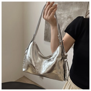 Macro view of metallic silver shoulder bag showing embossed MUDOU COLO DESING texture
