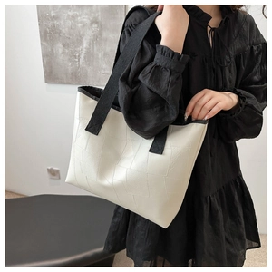 Close-up of geometric white tote bag featuring black contrast straps and textured leather