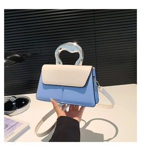 Détail du mini sac bicolore avec poignée métallique argentée au design artistique