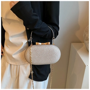 Close-up of silver sequin clutch bag with golden bow clasp and round metal handle