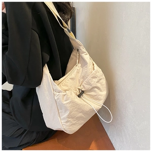 Detail of off-white nylon crescent bag with adjustable drawstring and wide strap on model