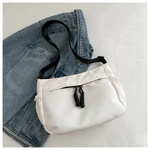 Détail d'un sac en nylon blanc avec fermetures noires sur un fond en jean bleu
