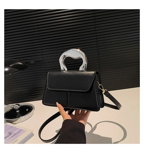Détail du sac à main noir avec poignée argentée irrégulière et texture en cuir