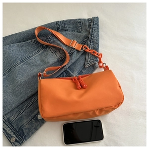 Detail of bright orange nylon shoulder bag with thick chain strap and zipper pulls