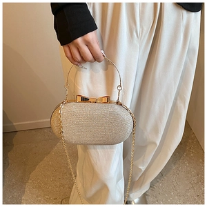 Detail of silver glitter evening clutch with gold handle and bow clasp on chain