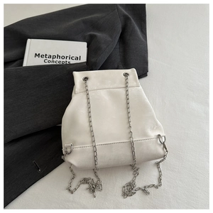 Detailed view of a white PU leather bucket backpack with elegant silver chain straps