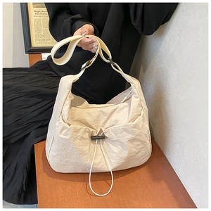 Close-up of beige nylon crossbody bag featuring drawstring pocket and adjustable strap