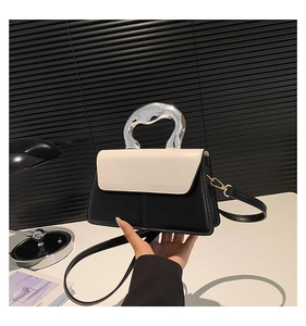 Détail du sac en cuir avec surpiqûres, poignée ondulée argentée et bandoulière