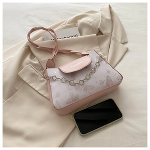 Detail of pink shoulder bag with butterfly print and decorative metal floral chain