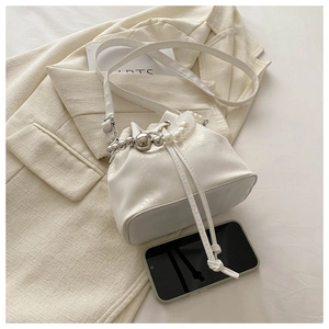 Detail of white glossy drawstring bucket bag with pearl and silver bead handle