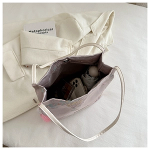 Vue de dessus d'un sac cabas violet brodé montrant l'intérieur spacieux avec des objets