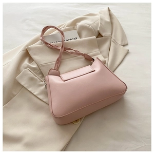 Detail of light pink leather shoulder bag with unique twisted strap on a blazer