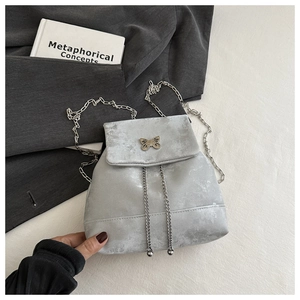 Close-up of silver backpack with metallic finish and decorative golden butterfly buckle