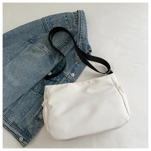 Vue détaillée d'un sac à bandoulière en nylon blanc avec sangle noire et plis latéraux