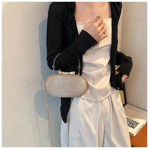 Detail of champagne gold evening clutch with bow clasp and metal ring handle