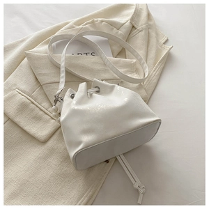Detailed view of white bucket bag featuring large pearl charm and drawstring metal eyelets