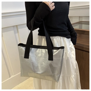 Close-up of metallic silver tote bag with geometric texture and black shoulder strap
