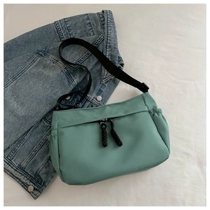 Détail du sac bandoulière vert menthe avec sangle réglable posé sur une veste en jean