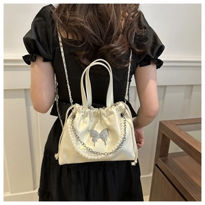 Detail of cream satin drawstring bag with pearl chain and silver butterfly buckle