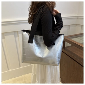Close-up of geometric metallic silver tote bag featuring black wide textile shoulder strap