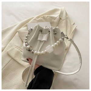 Detailed view of cream drawstring bucket bag with pearl and metallic bead handle decoration