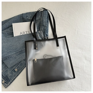Vue détaillée du sac cabas transparent en PVC avec pochette noire sur tissu texturé