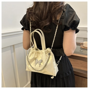 Detail of cream white bucket backpack with 3D butterfly ornament and pearl chain