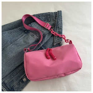 Detail of pink nylon crossbody bag with chunky plastic chain and woven rope zipper pull