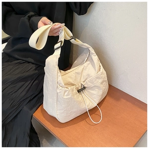Detail of beige nylon crossbody bag featuring drawstring texture and adjustable buckle strap