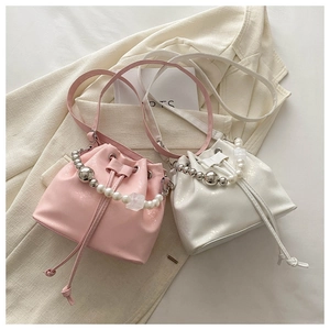 Detail of pink and white patent leather bucket bags with pearl handles and drawstring closure