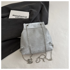 Detail of silver chain strap and metallic textured surface on a minimalist fashion bag