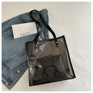 Détail macro du sac cabas noir translucide avec motif ours et rivets dorés sur la poignée