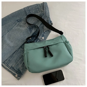 Détail du sac bandoulière en nylon vert menthe avec fermeture tissée noire et large sangle