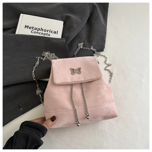 Detailed close-up of a pink velvet mini backpack with a silver butterfly chain ornament