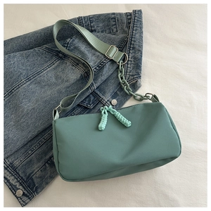 Mint green nylon crossbody bag with chic chain strap on a stylish denim jacket