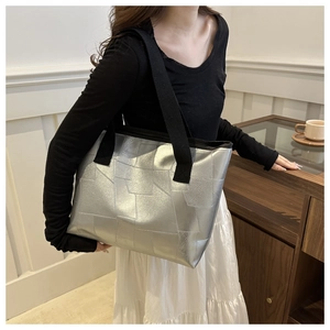 Detail of silver metallic tote bag with geometric stitching on a model's shoulder