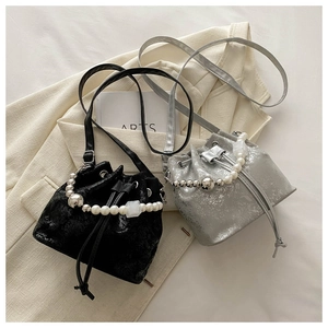 Close-up of stylish bucket bags with pearl handles and drawstring closure in black and silver