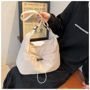 Detail of cream nylon crossbody bag featuring a functional drawstring pocket and wide strap