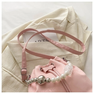 Detail of pink drawstring bucket bag with pearl and silver bead handle and metal texture
