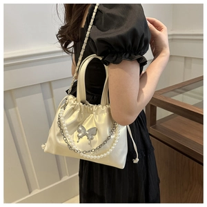 Detail of cream satin drawstring bucket bag with pearl chain and silver butterfly charm