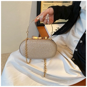 Macro shot of gold evening clutch bag with sparkling texture and bow metal clasp