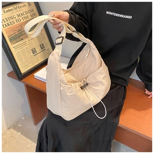 Detail of cream nylon crossbody bag with drawstring pocket on a side-facing model