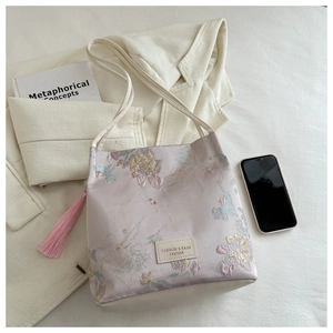 Détail de la broderie florale et de l'étiquette en cuir sur un sac cabas lilas