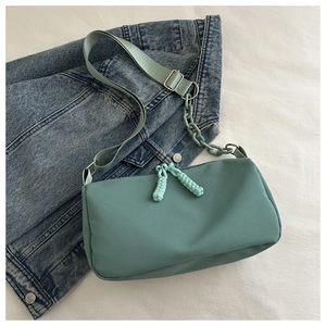 Detail of mint green crossbody bag with acrylic chain on denim jacket background