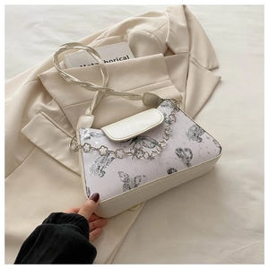 Detail of cream shoulder bag with grey butterfly prints and floral silver chain decoration