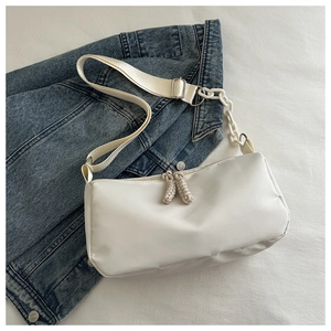 Detail of white nylon crossbody bag featuring chunky chain strap on denim jacket