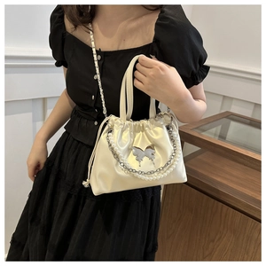 Detail of cream satin drawstring bucket bag with silver butterfly and pearl chain
