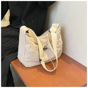 Close-up of beige nylon crossbody bag featuring drawstring pocket and canvas strap
